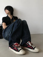 Black red distressed low-top sneakers worn seated look