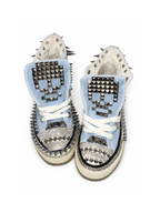 Baby-blue studded high-top sneakers with skull-studded tongues, front top view