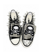 Black spiked low-top sneakers with skull-and-crossbones patches, top view